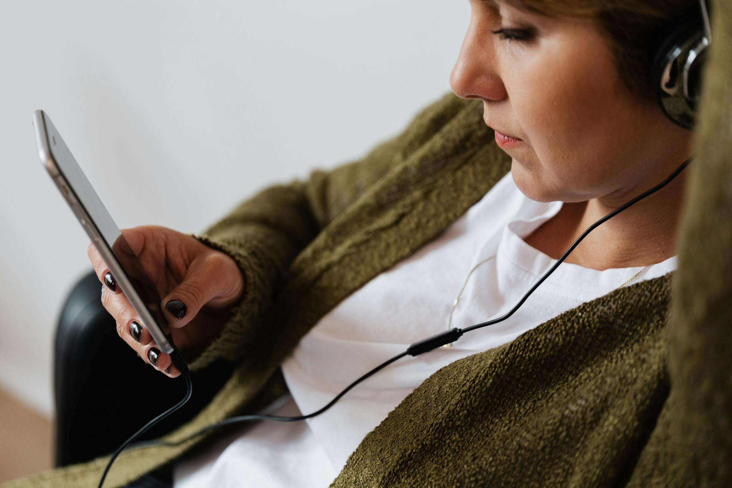 Woman using smartphone to control audio device settings from indoors