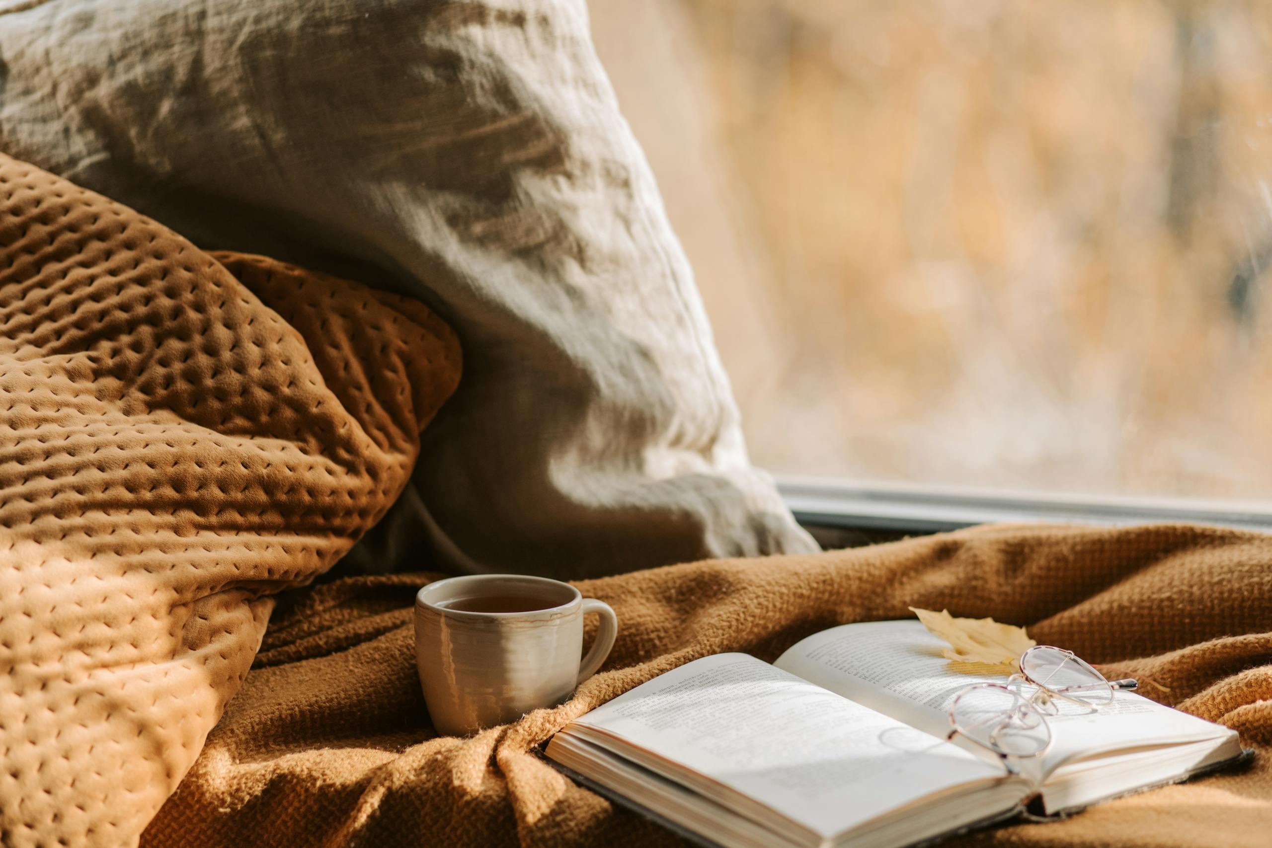 Cozy bedside table with book and warm drink creating calming evening routine atmosphere