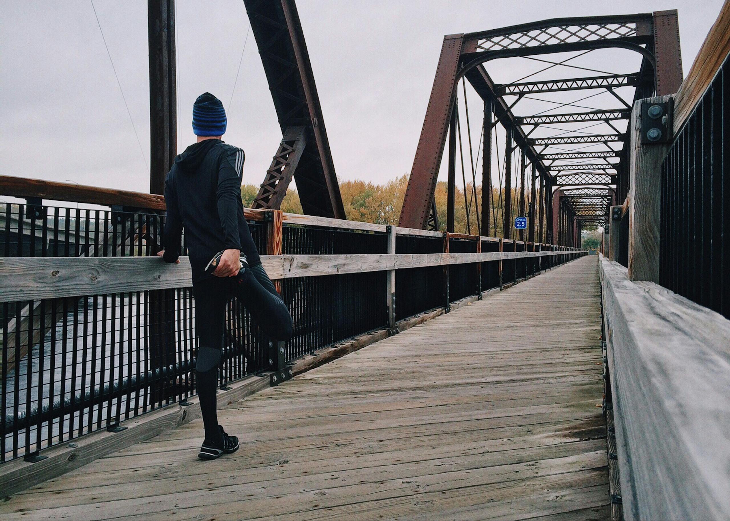 Athlete stretching on a bridge during outdoor training session in natural daylight