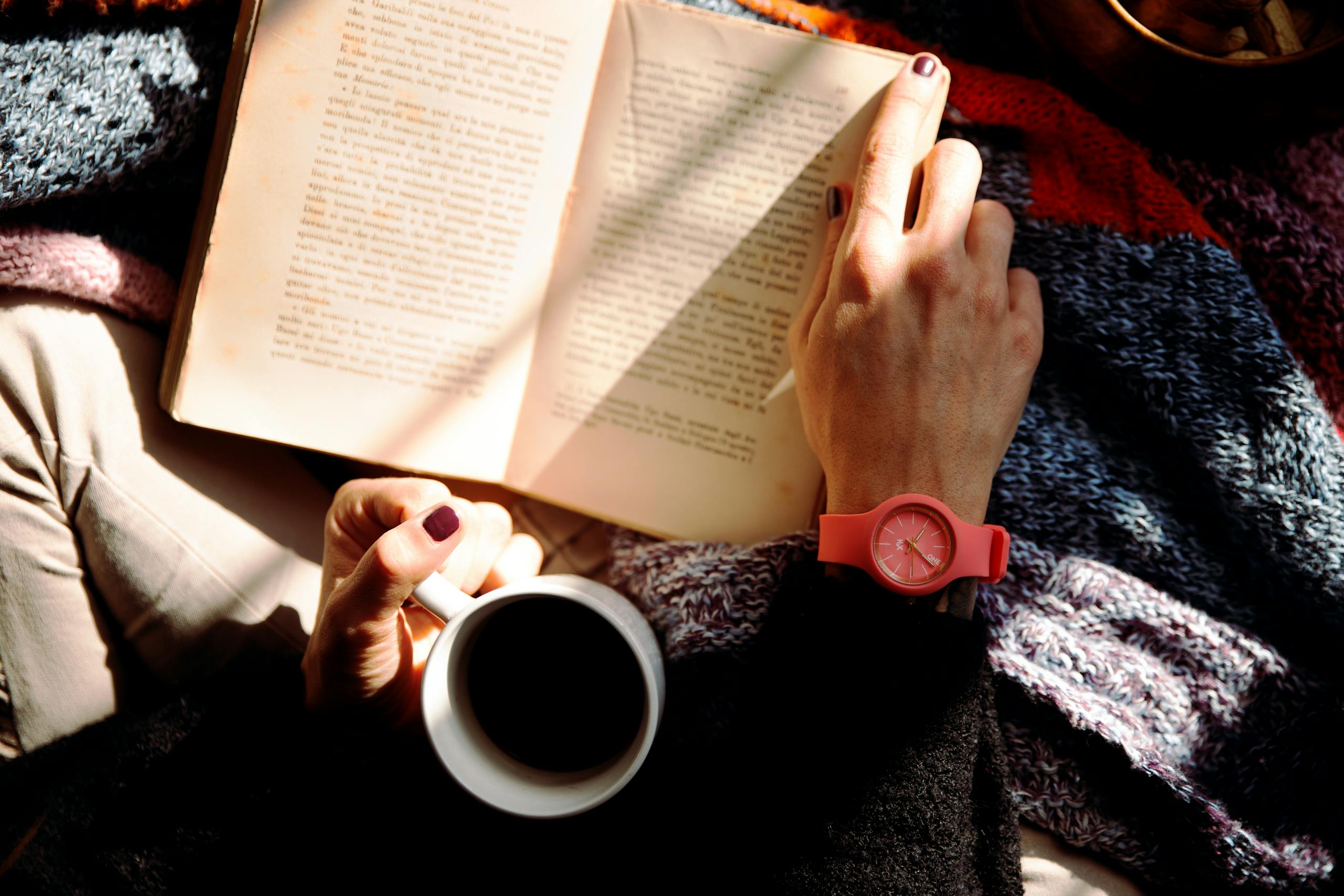 Relaxed person enjoying quiet moment with book and warm beverage at home