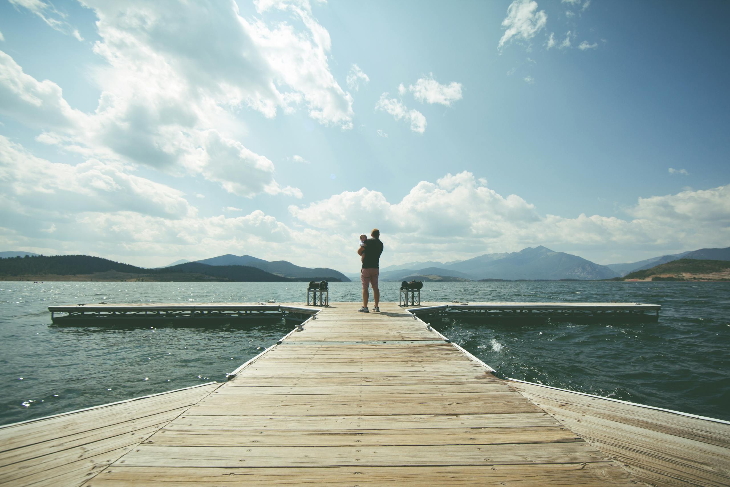Peaceful lakeside scene at dawn with mountains and clear sky representing natural light therapy