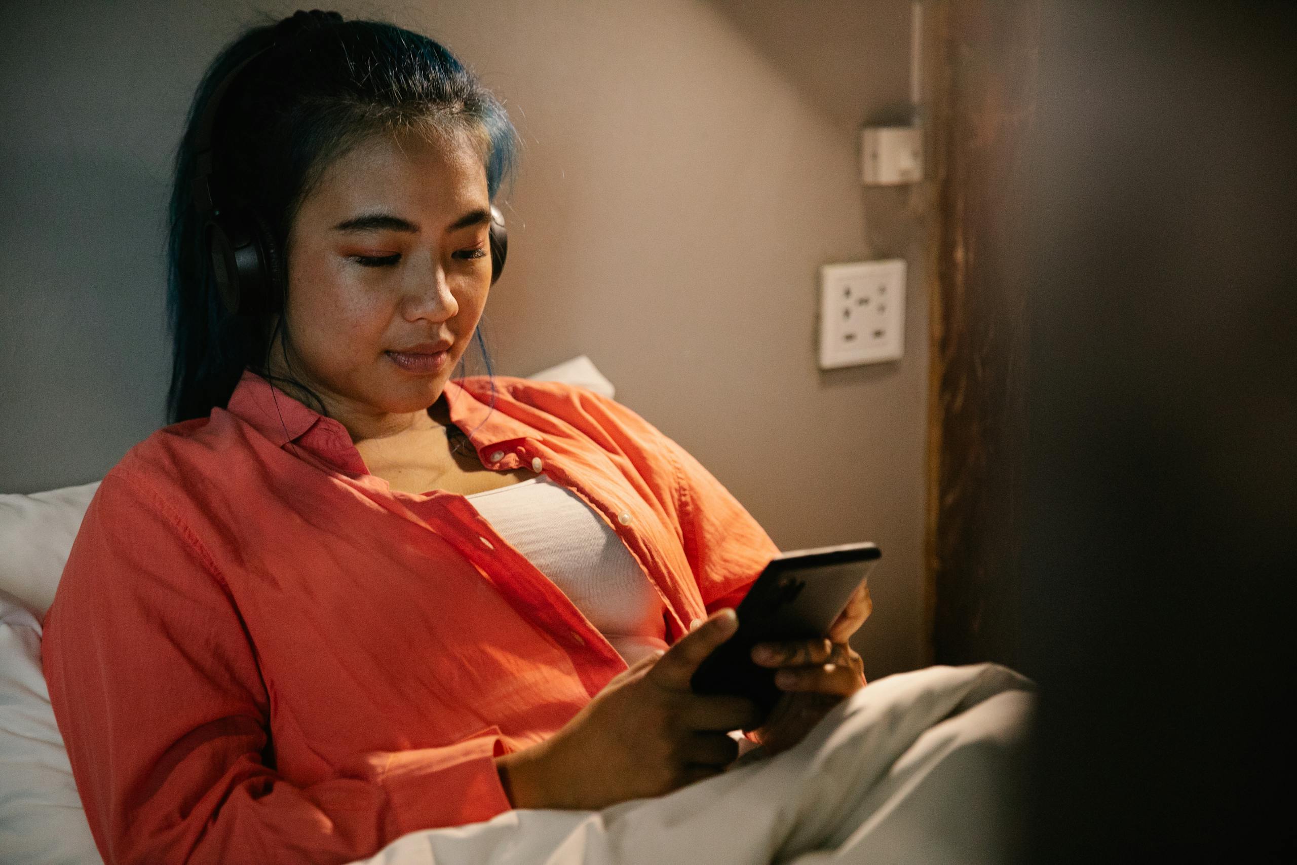 Person using wellness app on smartphone while journaling in calm evening routine for better sleep