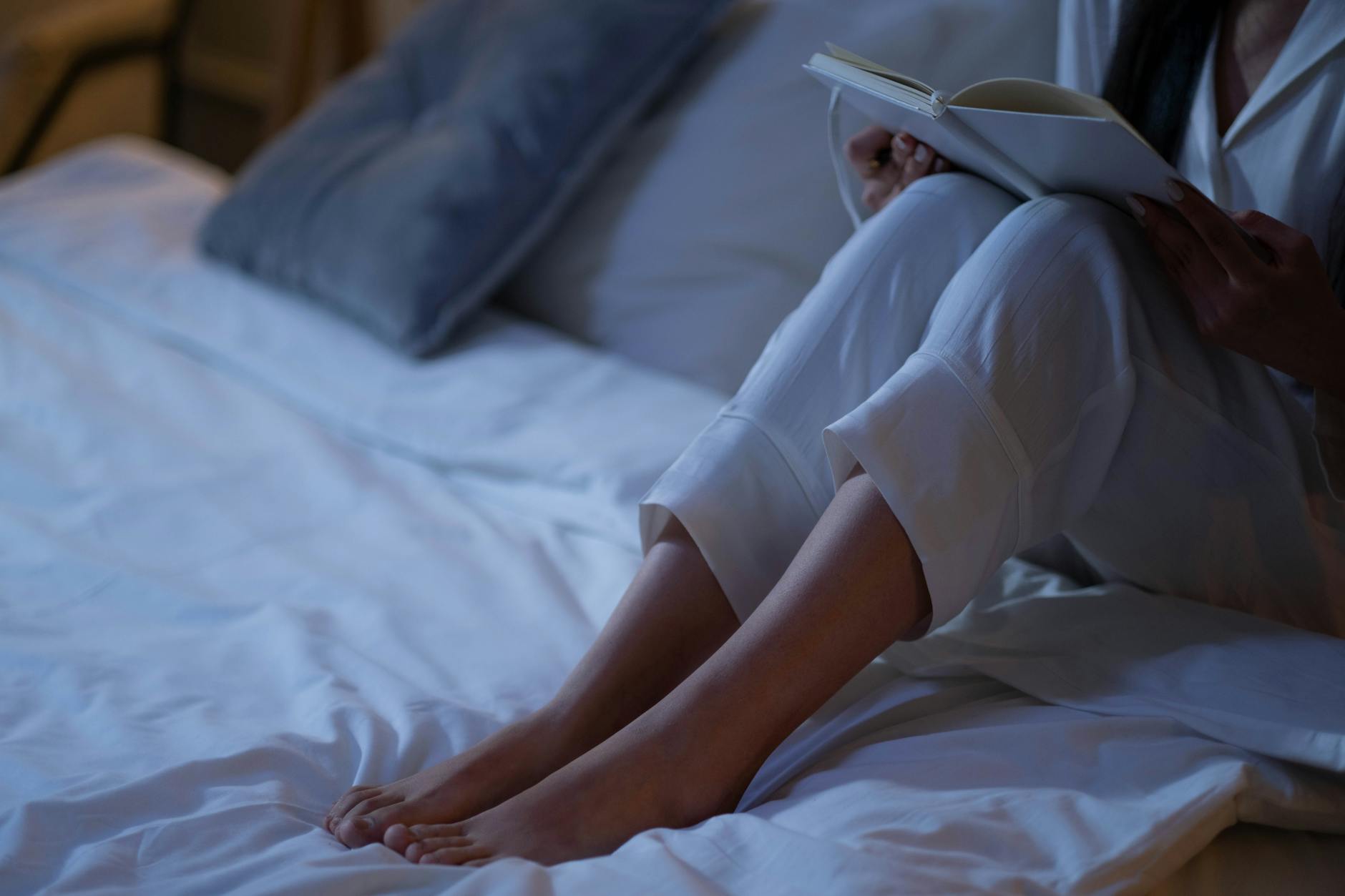 Person relaxing in peaceful bedroom reviewing health data on smartphone before bedtime routine